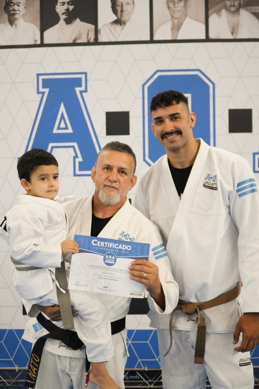 Mestre Renato Nato entrega certificado de graduação AOA a um aluno kids